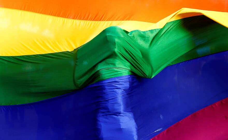 A participant stands behind a rainbow flag during a vigil in Mumbai, India, on June 16, 2016, held in memory of the victims of the Pulse nightclub shooting in Orlando, Fla.