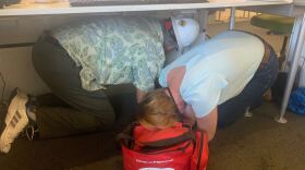Employees at KPBS practice taking cover under a desk, July 4, 2019.