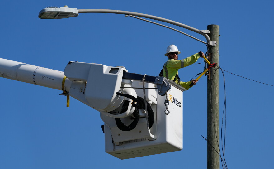 An electrical worker repairs power lines along a street in Gary, Ind, Thursday, Aug. 20, 2026, more than a week after a deadly storm passes through the area.