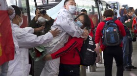 A medical worker from China's Jilin Province, in red, embraces a colleague from Wuhan as she prepares to return home at Wuhan Tianhe International Airport in Wuhan in central China's Hubei Province, Wednesday, April 8, 2020.