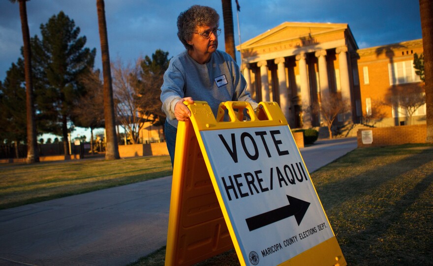 Election Day volunteer Vicki Groff places a sign to direct voters to a polling station at Kenilworth School in Phoenix in 2012.