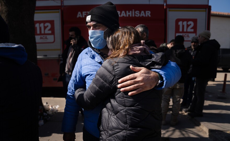 Sehmuz Sonmez holds his niece, Yasemin Arslan, as they wait with other family members outside a collapsed apartment building in Islahiye. Their relative remains unaccounted for in what's left of the building.
