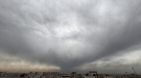 Plumes of smoke from a U.S.-Israeli strike on an oil facility late Saturday linger and merge with the cloudy sky over Tehran, Iran, Sunday.