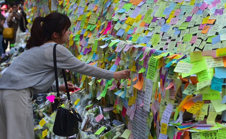 South Koreans leave notes at an exit of Gangnam subway station in Seoul. It was turned into a makeshift memorial for a 23-year-old woman who was stabbed to death by a male stranger.