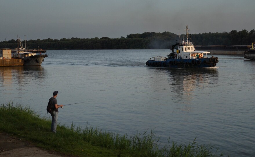 A man fishes near the port in Izmail as boats come and go on the Danube.