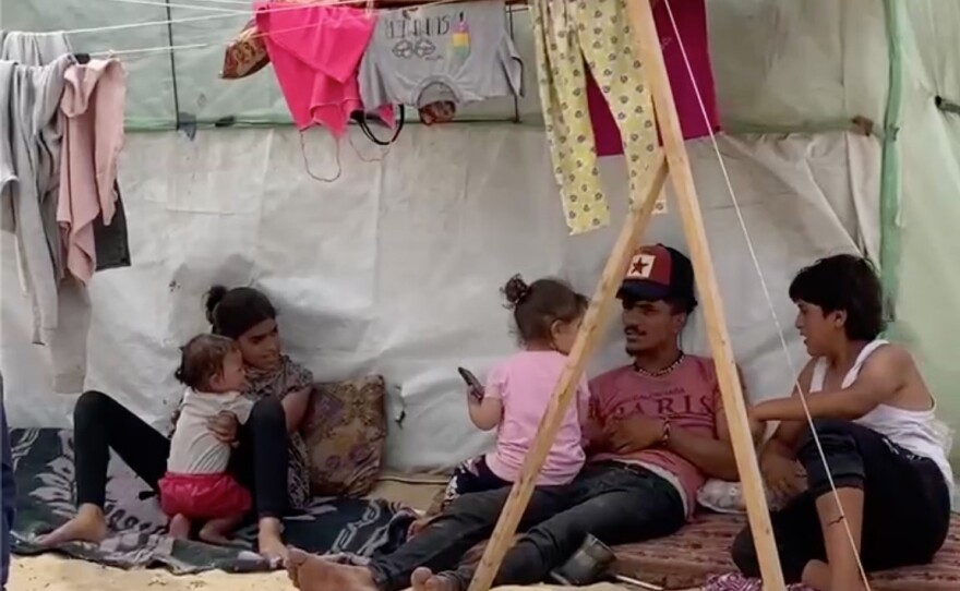 Displaced Palestinians in Rafah sit in the shade of their tent on a 100-degree day in the Gaza Strip.