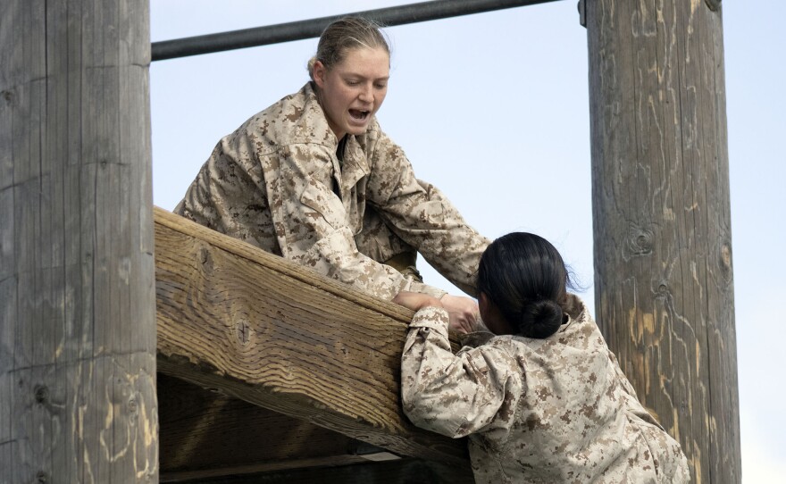 A Marine recruit helps a fellow recruit climb an obstacle during the confidence course, March 9, 2021.