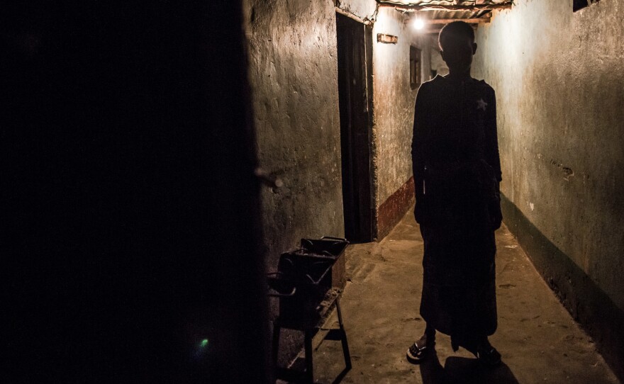 A sex worker waits outside a room she rents in Beira, Mozambique. Her client, inside, will pay 50 meticais for 5 minutes with her — that's about 75 cents.