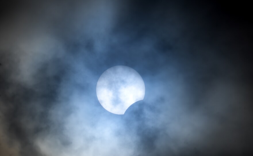 The moon begins to pass over the lower part of the sun during a total solar eclipse, seen from Pittock Mansion in Portland, Ore.