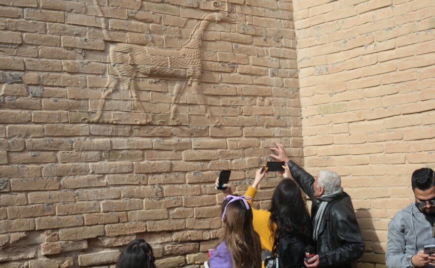 Visitors with the Bil Weekend tourism company take photographs inside the ruins of the ancient city of Babylon, in the area around the Ishtar gate. The animal on the walls ins a dragon-like creature associated with the Babylonian god Marduk.