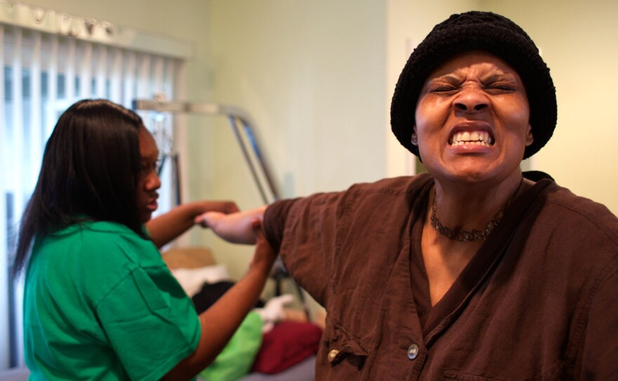 Loretta Jackson gently stretches the hands of her sister, Shirlene English, to aid physical rehabilitation after Sherline's brain aneurysm and stroke.