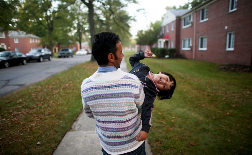 Omar Al-Awad holds his daughter as they walk home in Toledo, Ohio, where they were recently resettled after fleeing Syria and living in a Jordanian refugee camp. From the story "Among The Lucky Few: Syrian Family Rebuilds In America's Heartland," 2015.