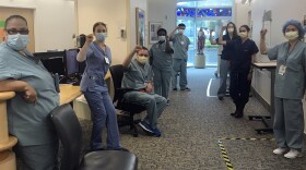 In this image provided by Lizabeth Baker Wade, nurses at Providence Saint John's Health Center in Santa Monica, Calif., on April 10, 2020, raise their fists in solidarity after telling managers they can't care for COVID-19 patients without N95 respirator masks to protect themselves. 