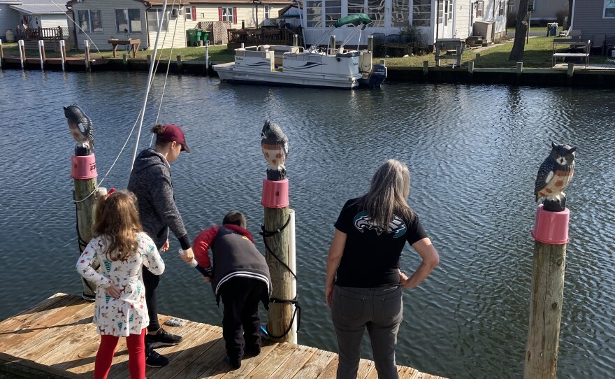 DeFrance on the dock outside her house in the mobile home park, with her daughter-in-law and grandkids.