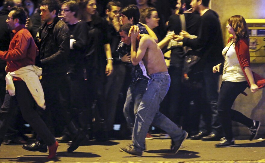 An injured man holds his head as people gather near the Bataclan concert hall.
