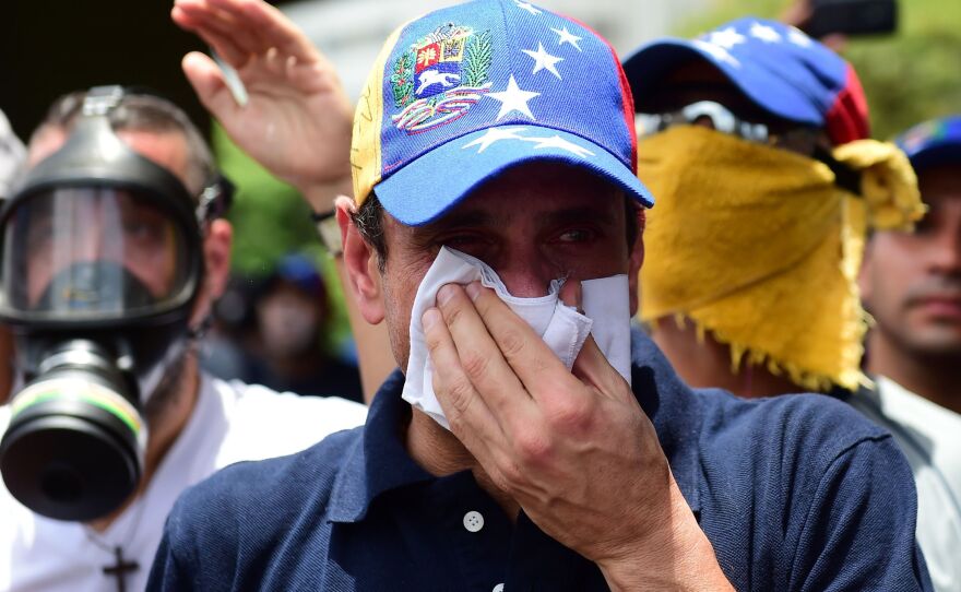 Opposition leader Henrique Capriles, who was banned from public office for 15 years, protects himself against tear gas during a rally against Maduro on Wednesday.