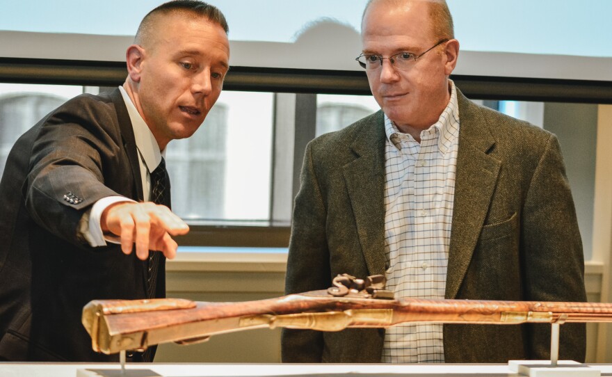 Special Agent Jake Archer of the FBI Art Crime Team (left) and William Perthes of the Barnes Foundation examine the rifle during its repatriation ceremony.