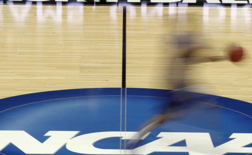 A player streaks across the NCAA logo at midcourt during basketball practice in this file photo from March 14, 2012.