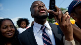 Wyclef Jean and his wife, Marie Claudinette Jean, walk through a crowd of supporters before he submitted paperwork to run for president of Haiti.