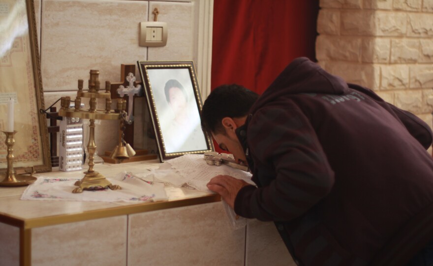 An Assyrian Christian man kisses a cross after taking communion in Tell Tamer, Syria. A photograph shows one of at least three people killed after ISIS took about 300 people captive in March 2015.