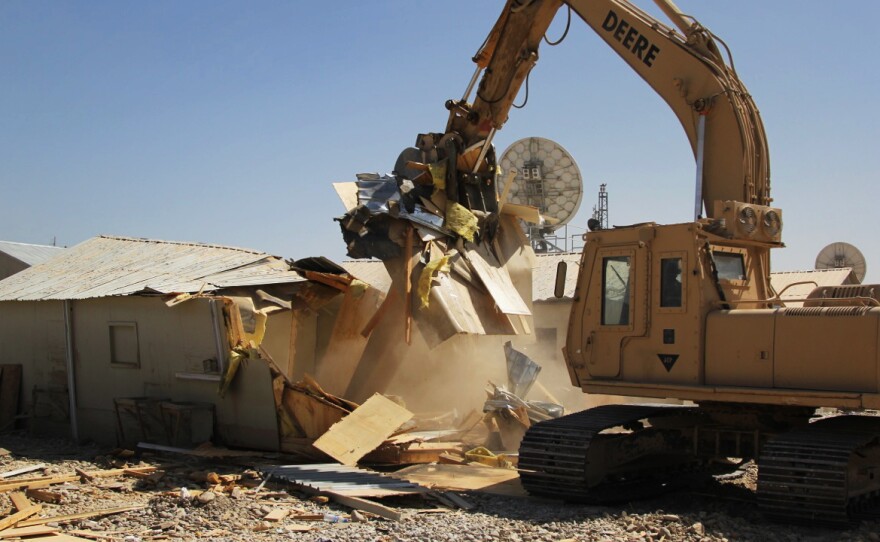 A construction excavator demolishes a so-called B-Hut at the huge Bagram Air Field norht of Kabul. The military used the structures as bunks and offices during the 13-year war but is tearing them down as most of the military prepares to leave by year's end.