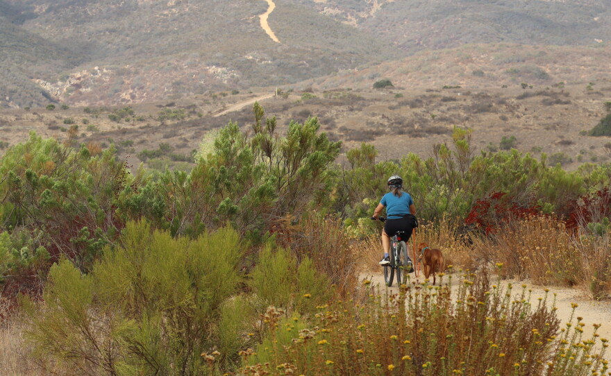 A woman rides a bike with her dog in Mission Trails Regional Park on Wednesday, Sept. 23, 2026.