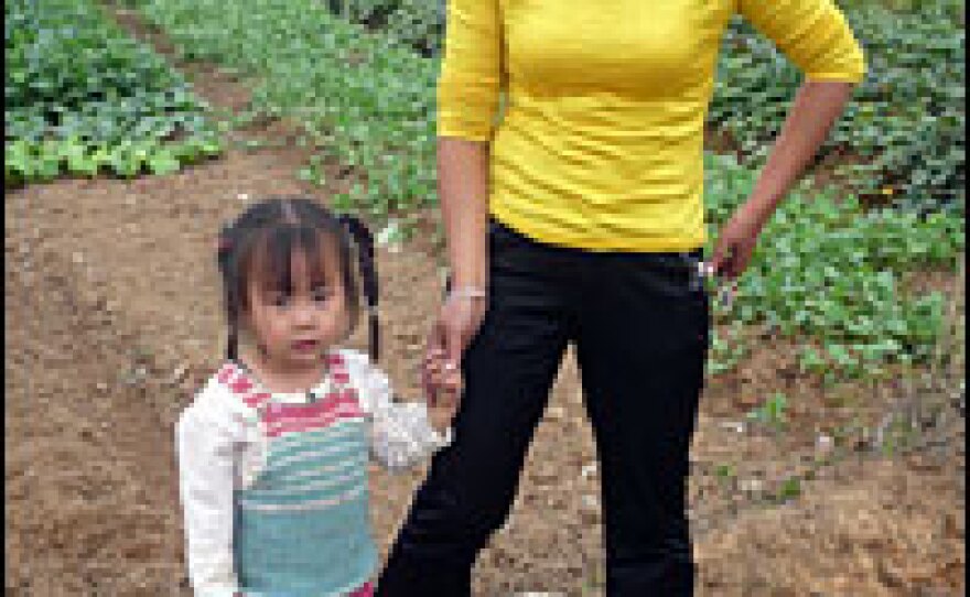 Huang Qing left the village with her husband six years ago. Visiting on vacation, she supports the land reform. "It's tough for the old people left behind to do the farming," she says.