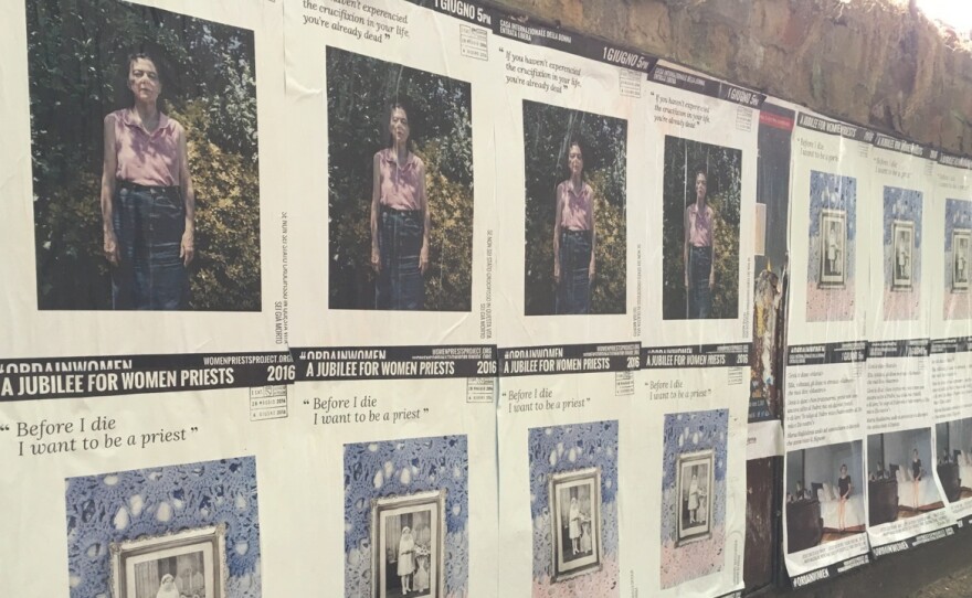 Posters touting the Women Priests Project along a wall.