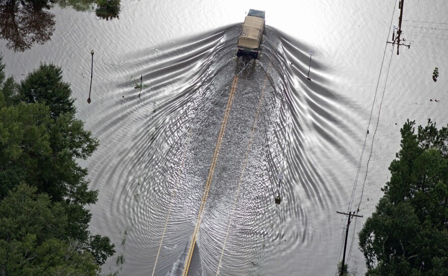 Army National Guard vehicles drive on flooded U.S. Route 190 in Robert, LA. on Saturday.