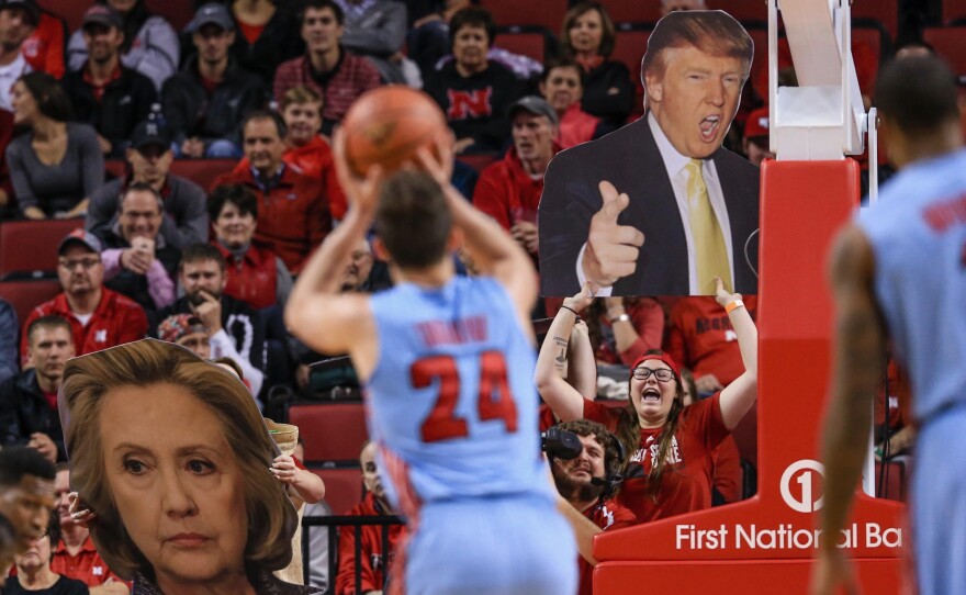 Nebraska basketball fans wave signs with the images of Donald Trump and Hillary Clinton. Nebraska neighbors Iowa, where Clinton and Trump are narrowly ahead days before the caucuses there.