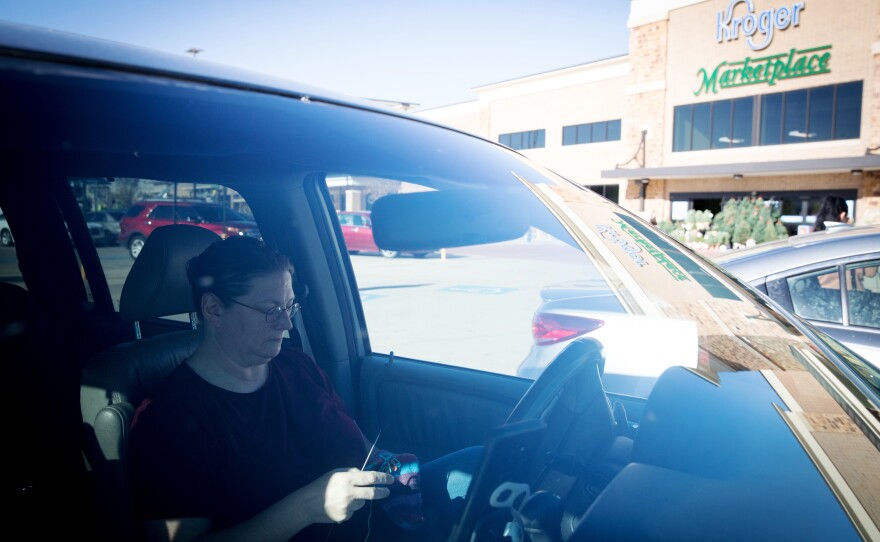 Teri Smith knits a pair of socks in a Kroger parking lot in Arlington, Texas, while she waits for Instacart to offer her a new grocery order. She signs up for shifts with Instacart five or six days a week.