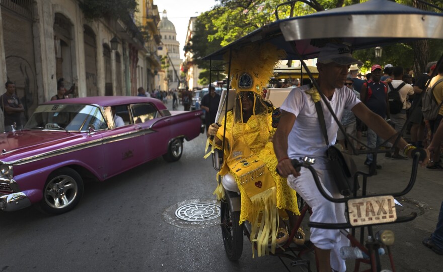 Cherice Harrison-Nelson, the Big Queen of the Mardi Gras Indians group the Guardians of the Flame, sits in traffic on a taxi bike.