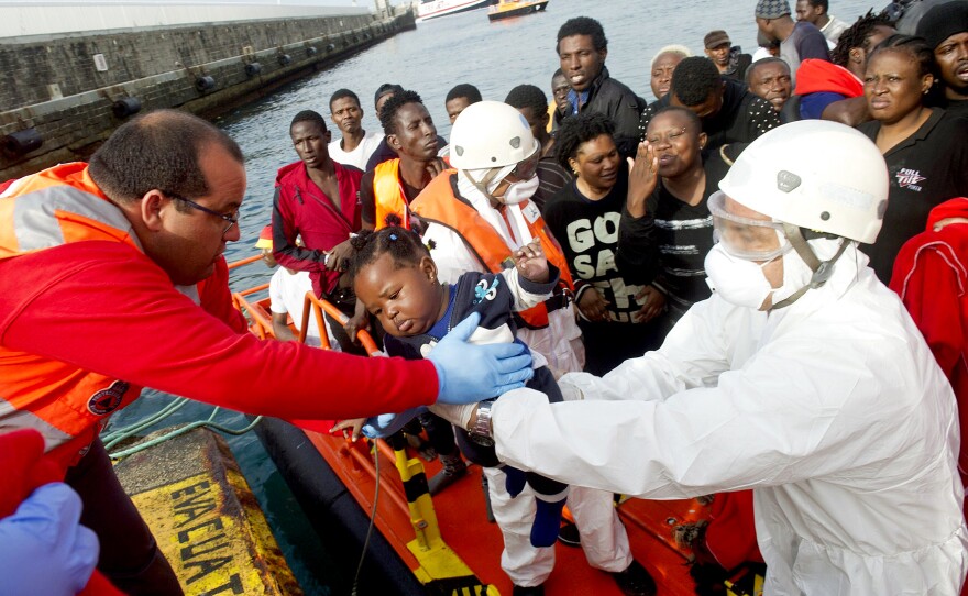 An African migrant infant is handed off by a member of the Red Cross to a member of the Spanish coast guard in the port of Tarifa on Tuesday.