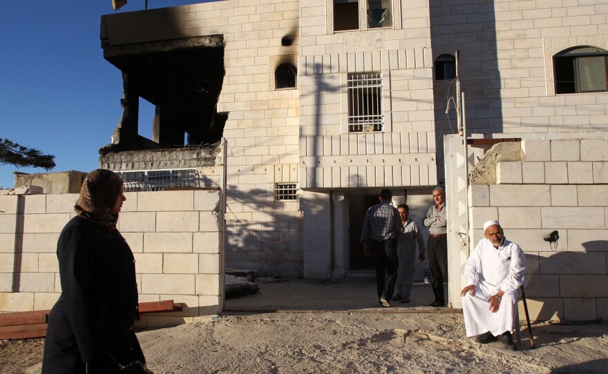 Relatives gather outside the damaged house of Amer Abu Eishe, a Palestinian member of the Hamas in Hebron whom Israel has named as one of two prime suspects in the murder of three kidnapped Israeli teenagers. The house was damaged in a raid.