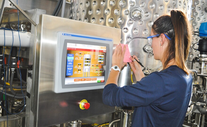 A student records information about a wine tank's sugar levels and juice temperatures on a computer screen inside UC Davis' research winery. In the future, students will also be able to monitor information about Clean in Place processes (which save water) using these screens.