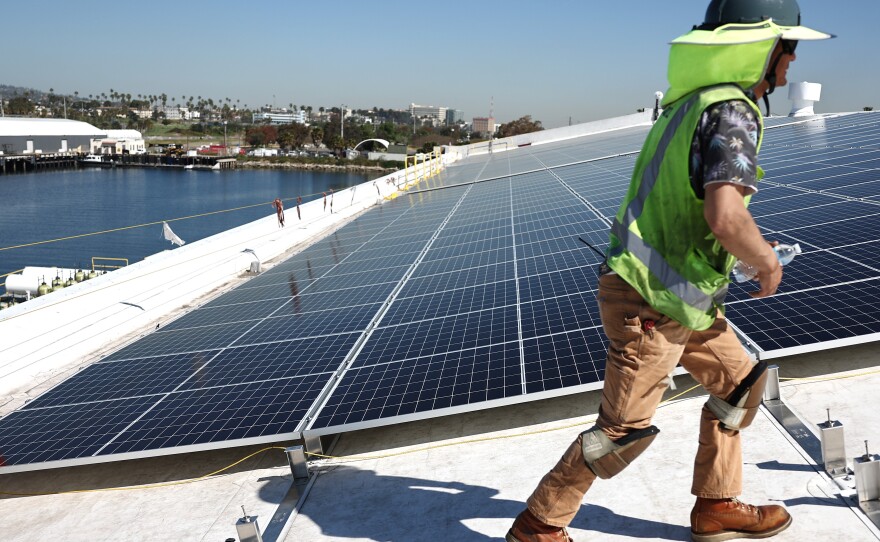 Workers install solar panels on a rooftop at AltaSea's research and development facility at the Port of Los Angeles on April 21, 2023.