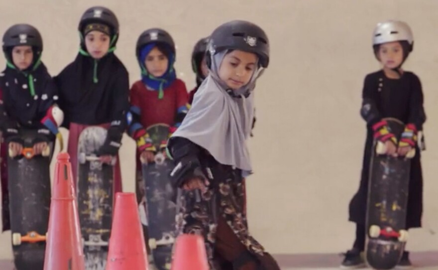 Students wearing headscarves and helmets learn to navigate traffic cones in a scene from the Oscar-winning documentary, "Learning to Skateboard in a Warzone (If You're a Girl)."