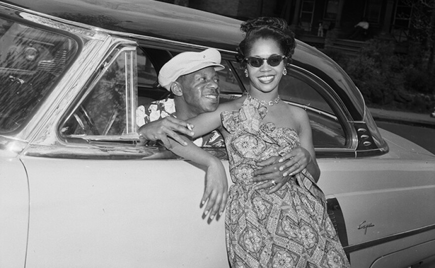 Woman posed against 1952 Lincoln Capri coupe car, with man leaning out of driver's side and wrapping his arms around her, Pittsburgh, Pa, c. 1952 - 1960.