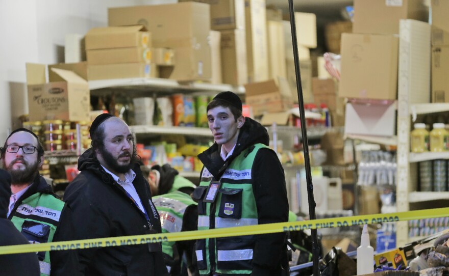 Emergency responders gather Wednesday morning behind police tape outside a kosher supermarket where a shootout left three bystanders dead one day earlier in Jersey City, N.J.