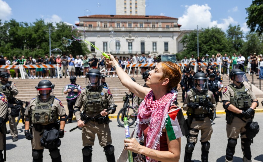 A pro-Palestinian protestor blows bubbles in front of a line of Texas State Troopers on April 29, at the University of Texas at Austin.