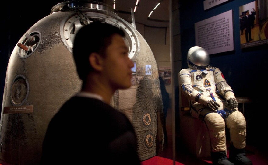 A visitor stands near the Shenzhou 5 re-entry capsule, used in China's first human spaceflight mission, and the spacesuit worn by crew member Yang Liwei, at an exhibition in Beijing on July 6.