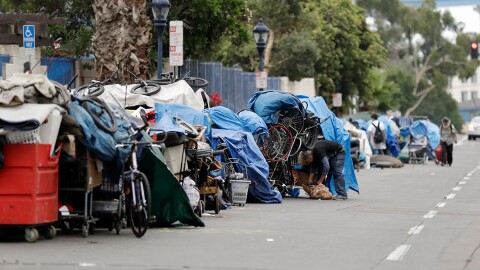 Homeless people stand among their items along 17th Street in San Diego, Sept. 19, 2017. 