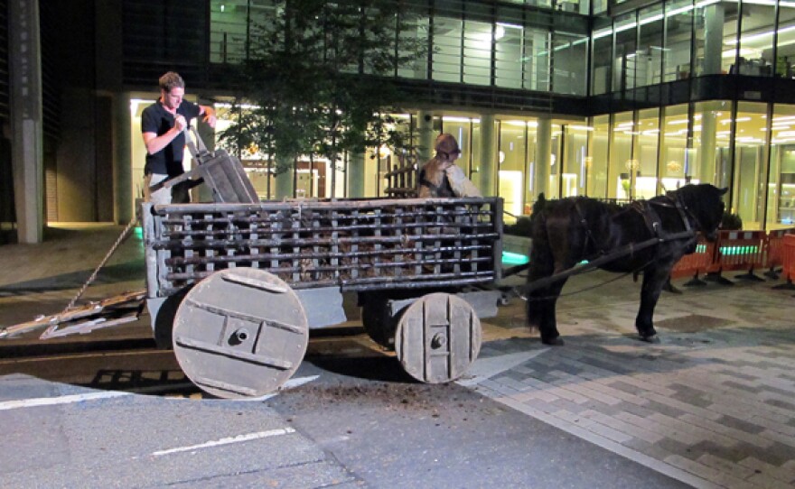 Host Dan Snow loading horse manure onto a horse cart.