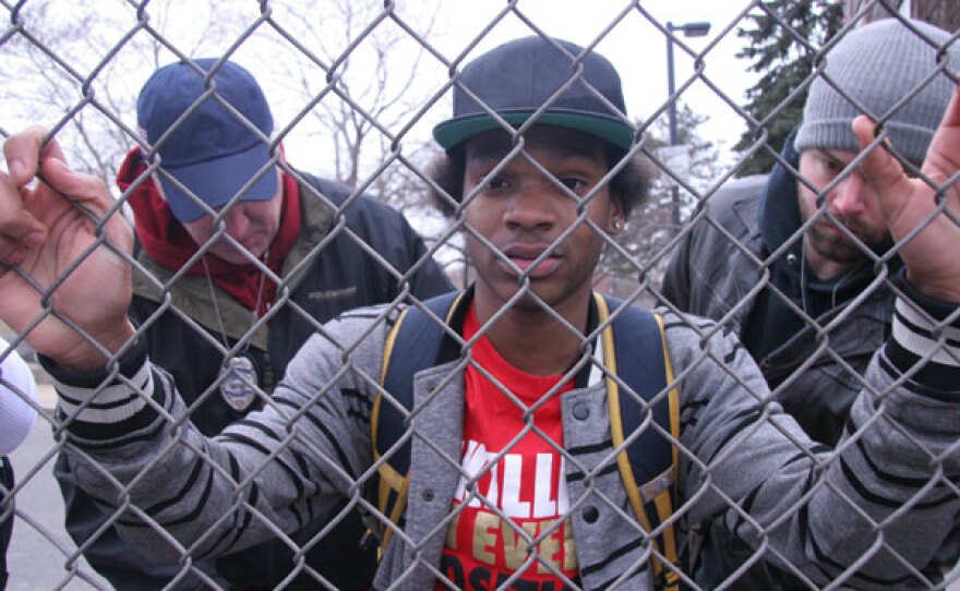 Reenactment photo of young man getting frisked by cops.