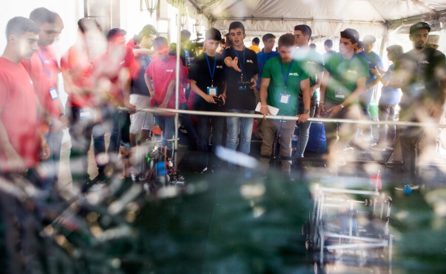 Competitors from Team Hope (center in black) test their robot in a designated practice area. The team of Syrian refugees who had fled to Lebanon drew cheers from the crowd.