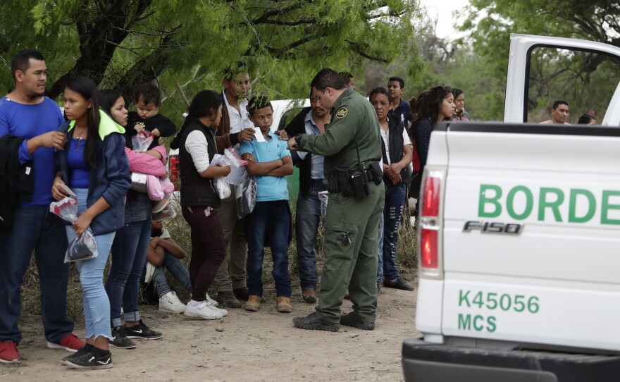 A Border Patrol agent checks the names and documents of families who crossed the nearby U.S.-Mexico border near McAllen, Texas. Immigration authorities say they expect the ongoing surge of Central American families crossing the border to multiply in the coming months.