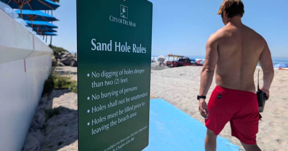 A lifeguard walks past a sign in Del Mar warning of the new rules against "hazardous holes" on the beach, March 19, 2026.