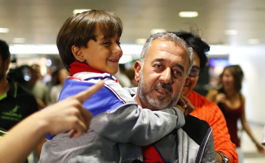 Osama Abdul Mohsen holds his son Zaid as they arrive at the Barcelona train station on Sept. 16, 2015.