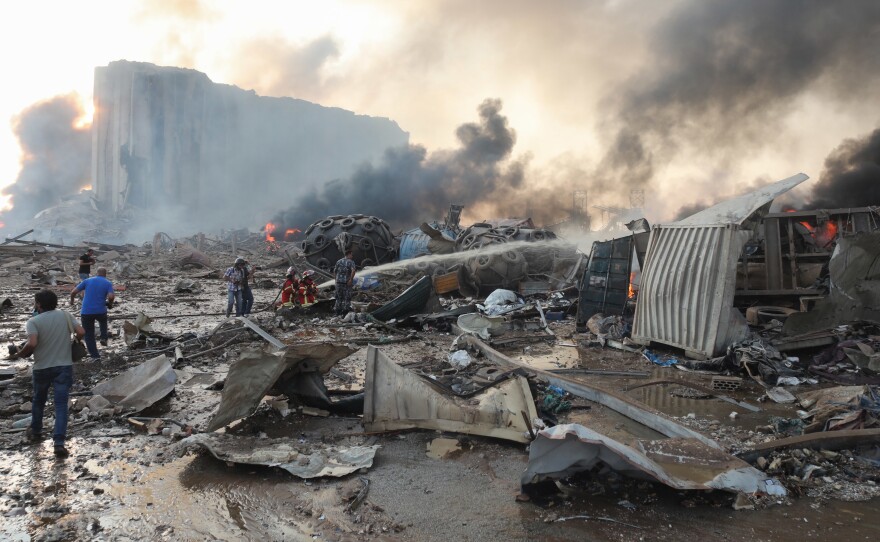 Firefighters extinguish flames at nearby damaged buildings following a large explosion at the Port of Beirut in Lebanon Tuesday. The massive explosion rocked the capital and its suburbs, sending a huge mushroom cloud into the skyline.