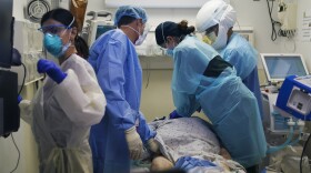 In this Nov. 19, 2020, file photo, emergency medical technician Giselle Dorgalli, second from right, performs chest compressions on a patient who tested positive for the coronavirus in the emergency room at Providence Holy Cross Medical Center in Los Angeles.